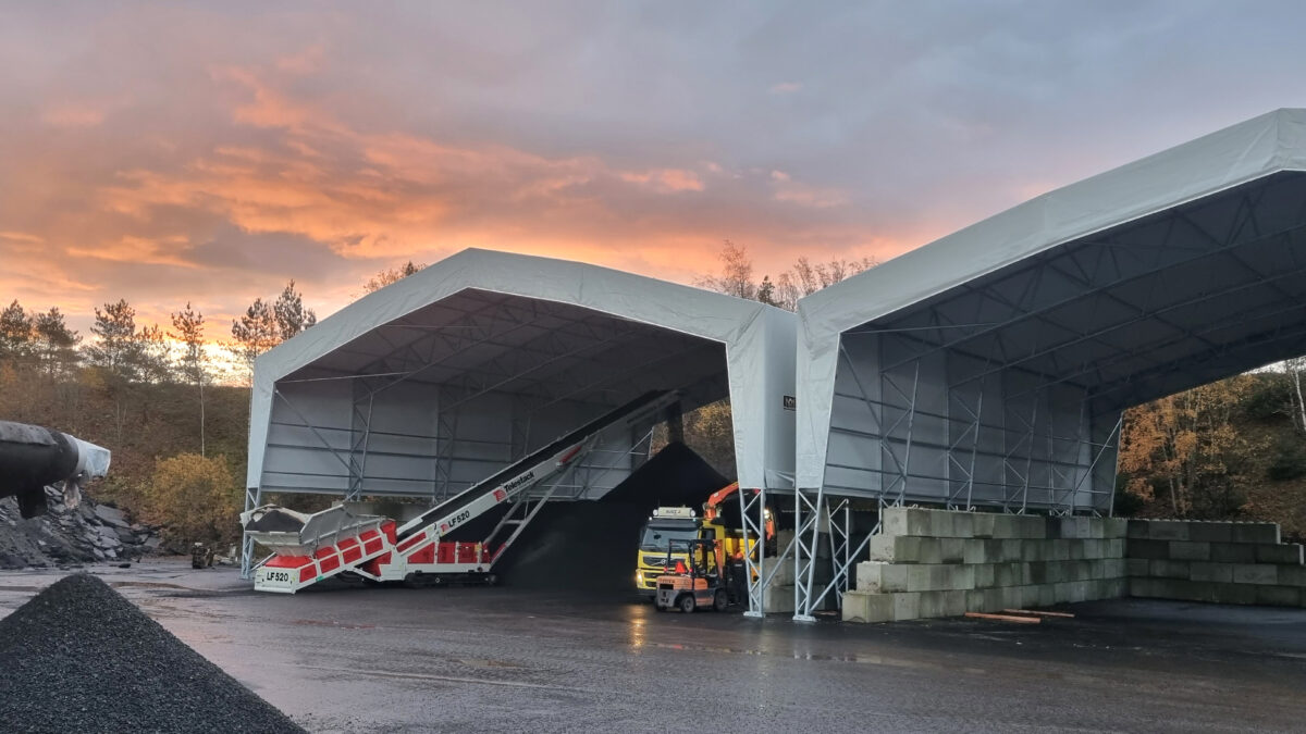 Två stora vita bulkhallar vid solnedgång, används för förvaring av material med hjälp av transportband. Hallgruppen erbjuder dessa hållbara lösningar.