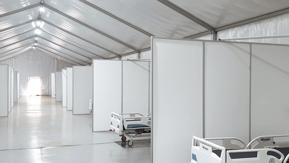 Vita haguhallstrukturer med sängar och panelväggar, inredda av Hallgruppen, redo för medicinsk användning.