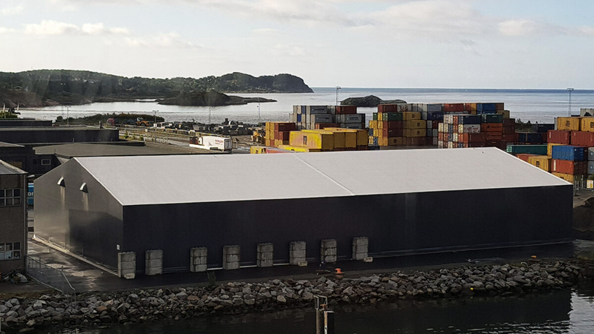 Hamnlager byggt av Hallgruppen, beläget vid vattnet, omgiven av containrar. Den robusta byggnaden är rymlig och välplacerad.