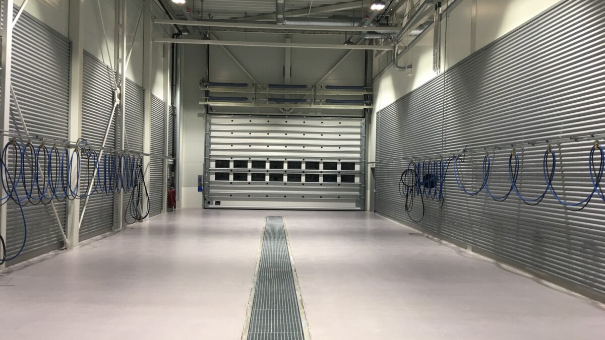 Interiör av en maskinhall med spolhall, utrustad med slangar och dräneringskanaler.