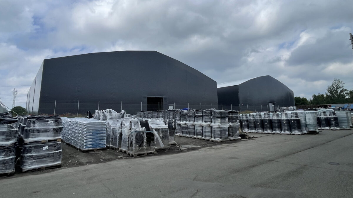 Hallgruppen har uppfört en stor svart täIthall med förpackat material utanför, under en molnig himmel.