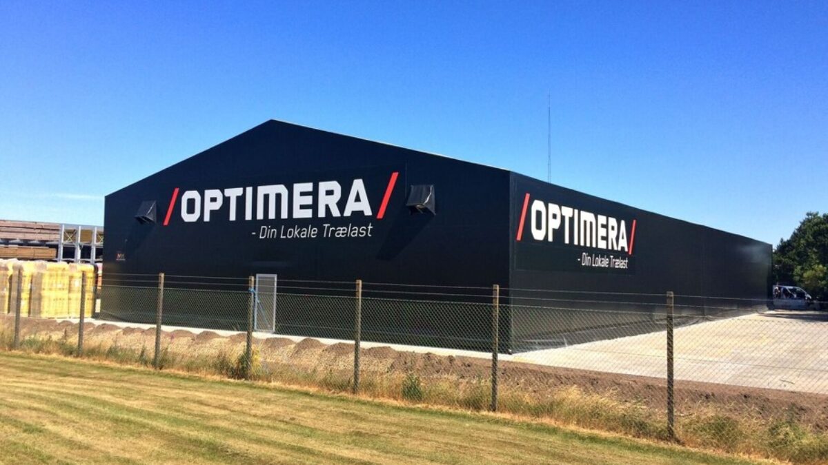 En svart täIthall med "Optimera" logotypen, byggd av Hallgruppen, står på en asfalterad yta under en klarblå himmel.