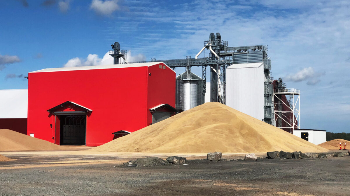 En stor röd täIthall från Hallgruppen står nära industriella strukturer och högar av material.