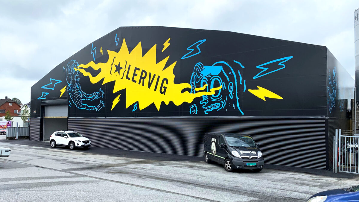 En tälthall designad av Hallgruppen med en kreativ muralmålning på fasaden. Hallen står på en parkeringsplats och används för lagring av varor.